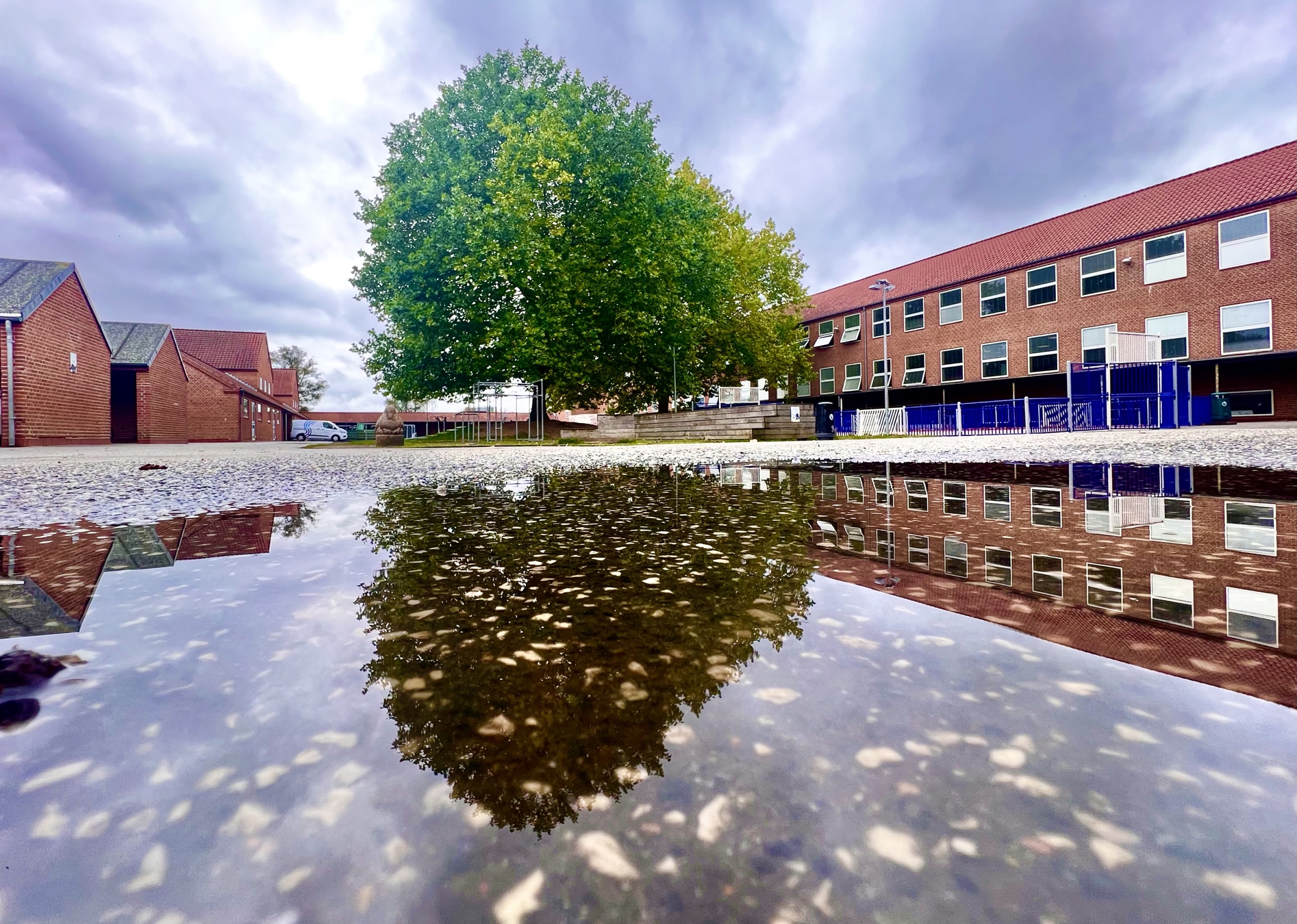 Skolegården på Vestergårdsskolen spejlet i en vandpyt